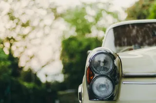 The headlight and body of a parked vintage car