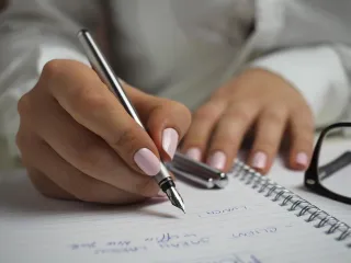 A person writing at a work desk