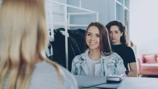 Shoppers interacting with a cashier at a clothing-store counter.