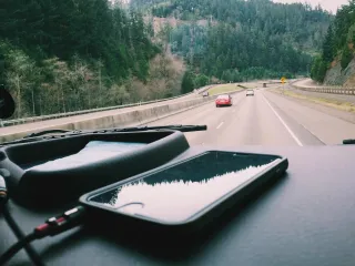 A phone and notebook on a car dashboard