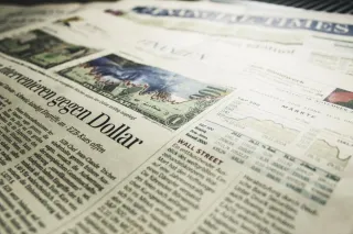 A business newspaper displays printed market tables and financial news.