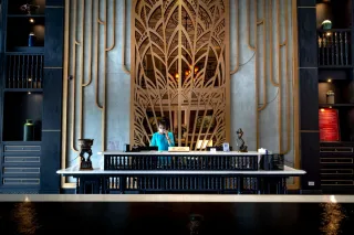 A receptionist behind an ornate hotel reception counter.