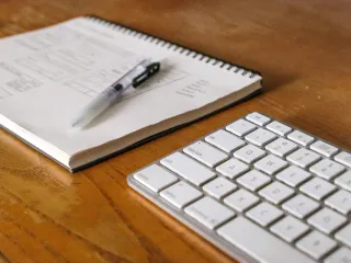 A notebook and pen beside a keyboard